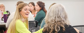 Attendee seated around a table during a networking discussion at a Women in Leadership event smiling