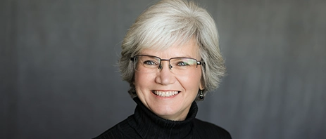 Kelly Ward, Director of Mount Mercy's ACE Center smiles into the camera against a dark background.