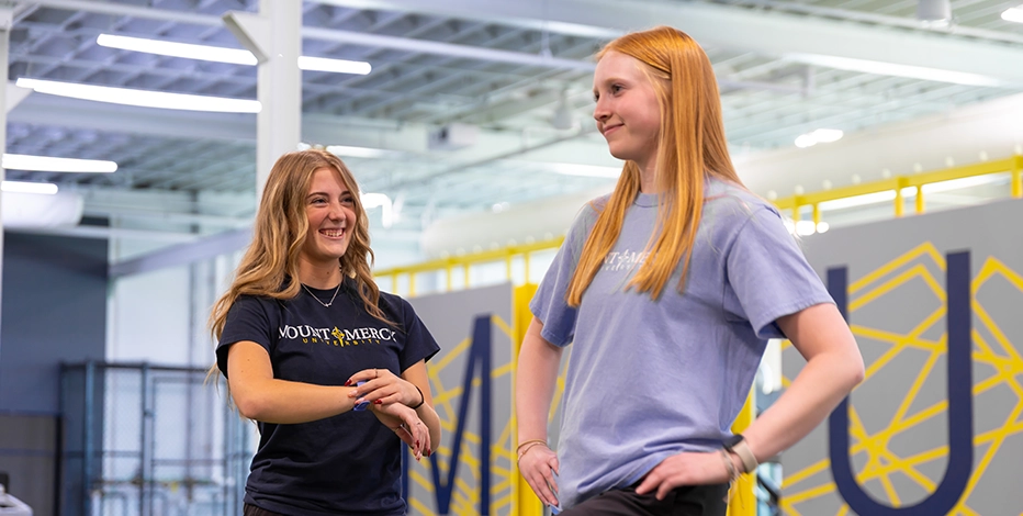 Two students stand in a campus fitness facility